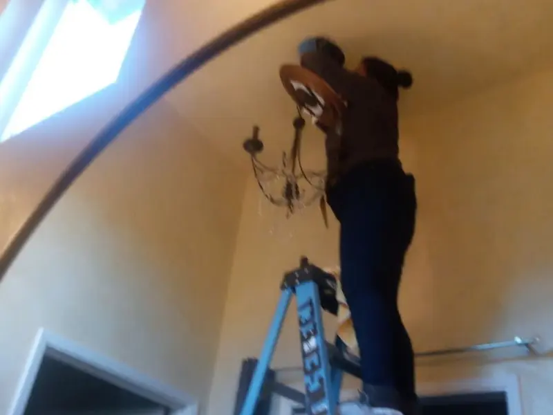 Electrician installing a chandelier in a Urbandale residence
